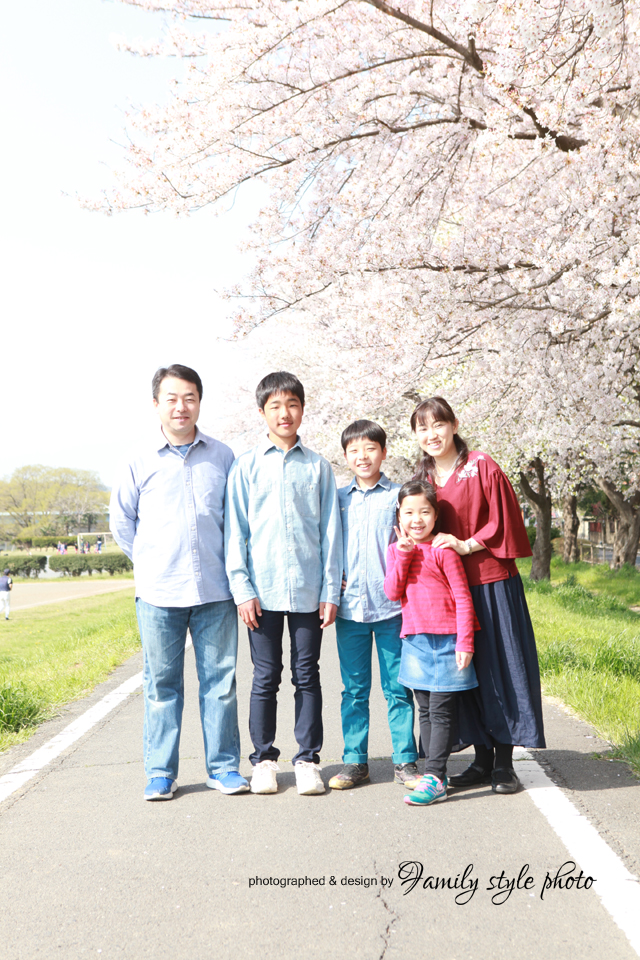 満開の桜の木を背景に笑顔で記念写真を撮る親子