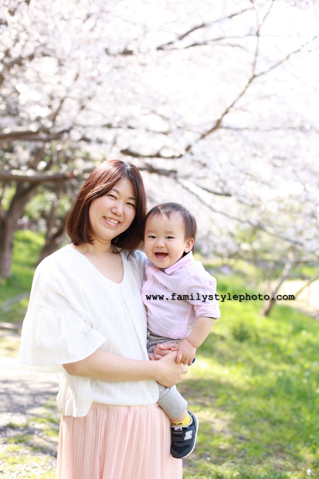 桜を背景に笑顔のカメラ目線の親子