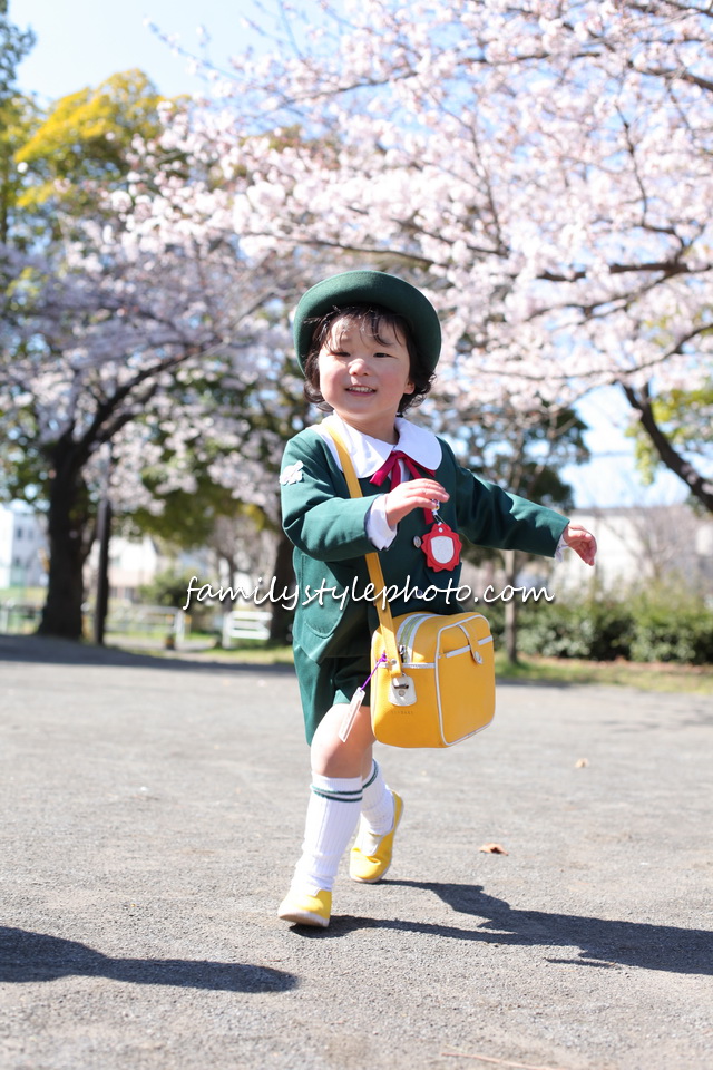 桜を背景に新しい園バッグを背負う幼稚園生