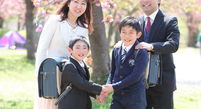 桜の下で入学記念の写真を撮る家族