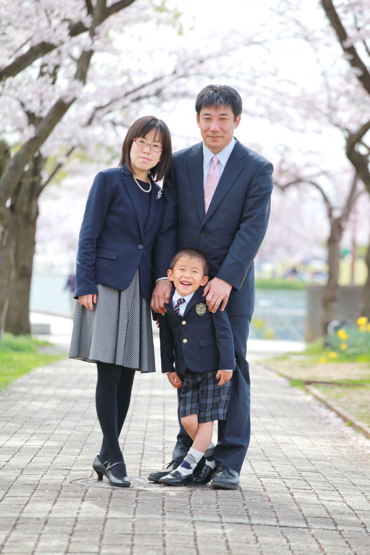 桜の木の前に立つ家族