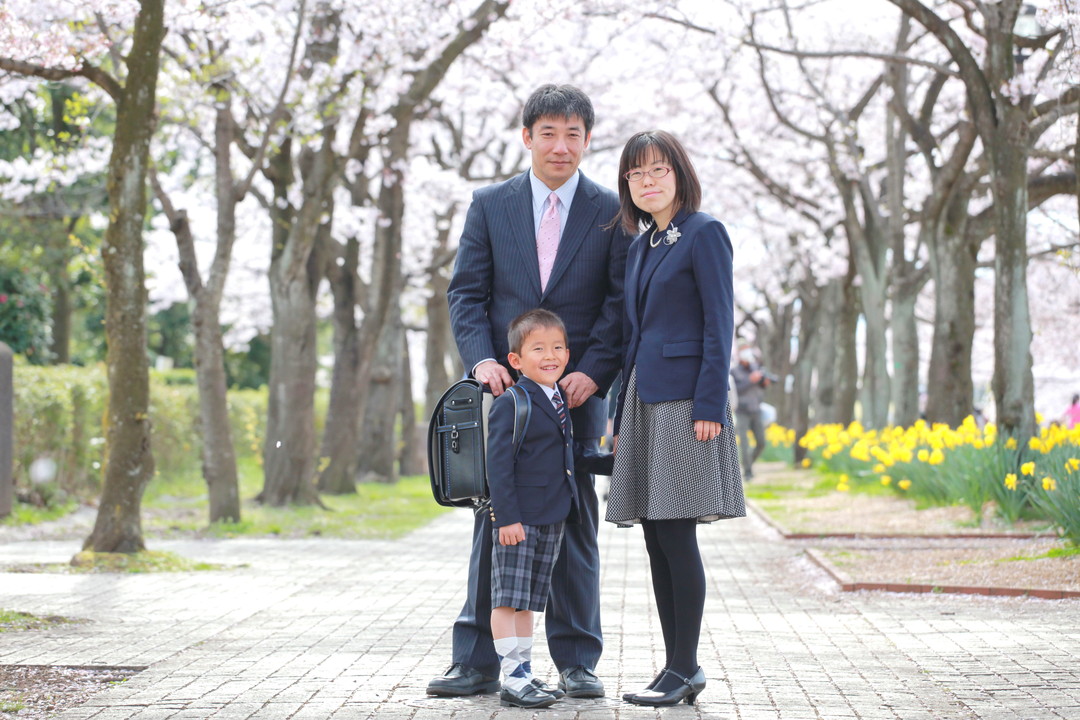桜の木の前に立つ家族